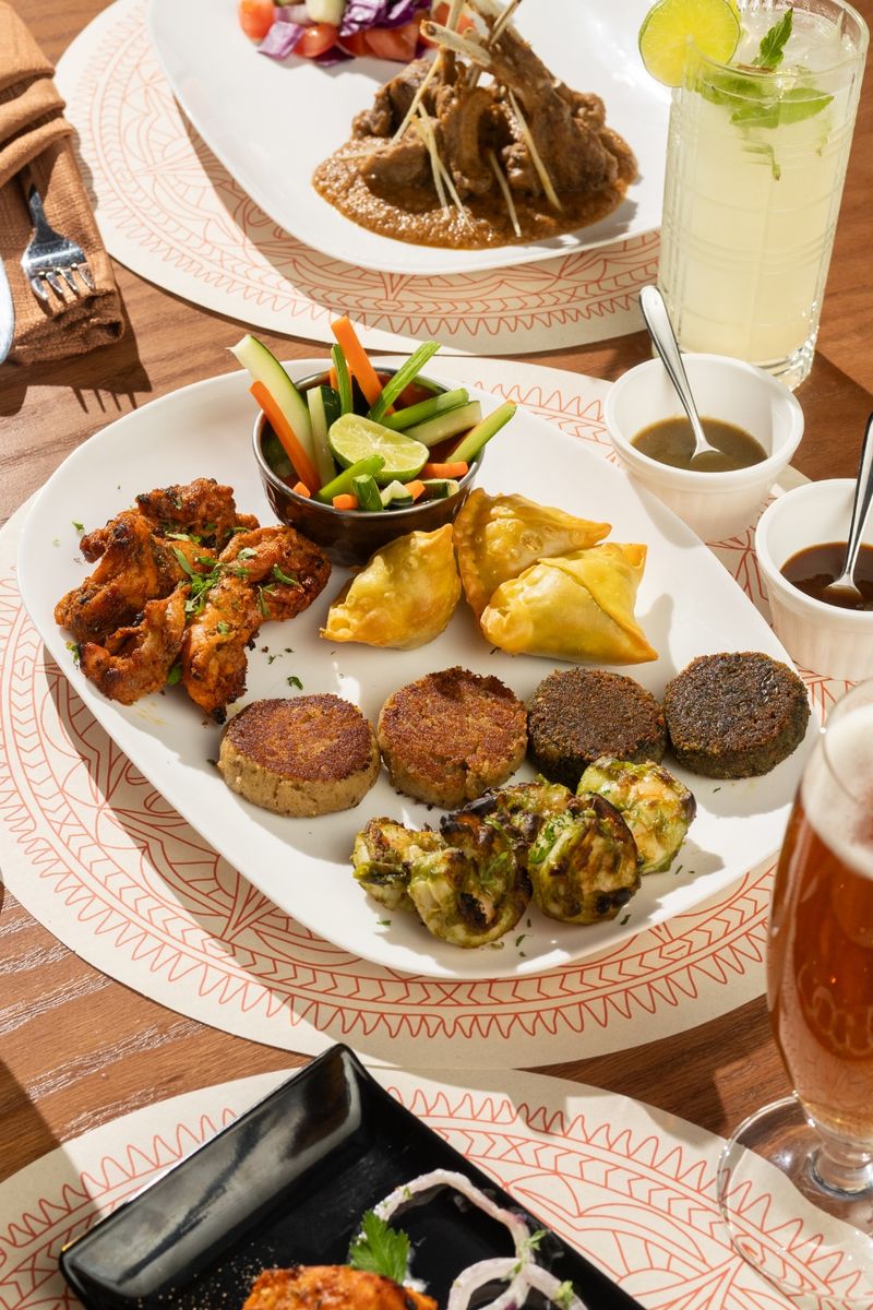 A shared starter platter of lamb chops, kebabs, and samosas